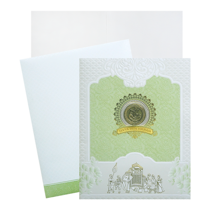 Green and White Bhaarat Wedding Card featuring a ganesha sticker, an acrylic nameplate embossed design and gold foiled bhaarat. It also includes a folded insert and an envelope.  Shop now! ?WhatsApp Support ?Express Delivery.